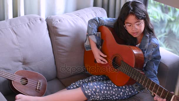Портрет молодої привабливої дівчини, в окулярах і джинсовій куртці, прослуховування музики з навушниками у вітальні — стокове відео
