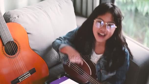 Retrato de niña atractiva, con gafas y chaqueta de jean, escuchando música con auriculares en la sala de estar — Vídeos de Stock