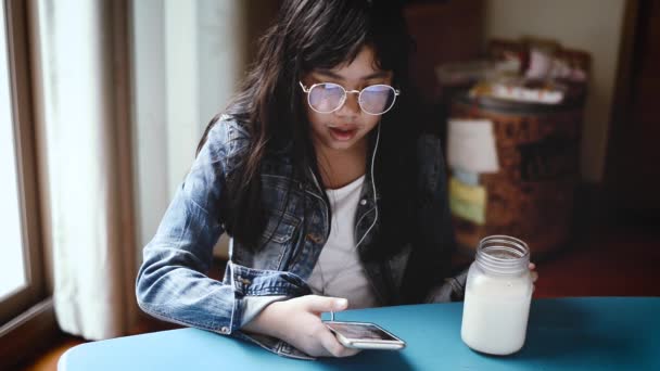 Portré, mosolygós lány, zenét hallgatni, és a tej a nappaliban. Bajusz tej — Stock videók