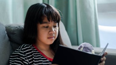 Kitap okuma bebeğini evde, sevimli küçük kız yumuşak odak sho