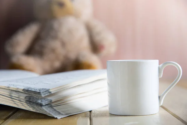 Kaffeetasse und Buch über Teddybär im unscharfen Hintergrund — Stockfoto