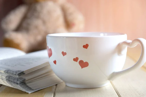 coffee cup and book focused on teddy bear in Blurred background