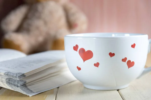 coffee cup and book focused on teddy bear in Blurred background