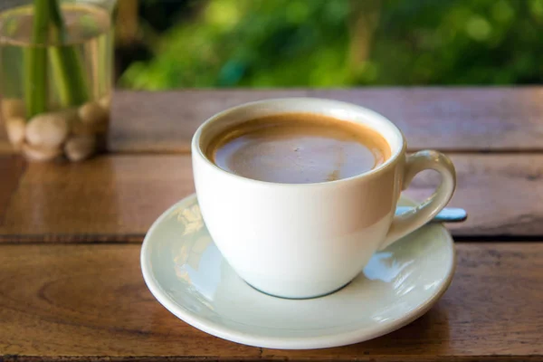 Tazza di caffè fresco con chicchi di caffè sul tavolo di legno — Foto Stock