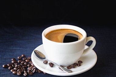 Kahve fincanı ve karanlık bir arka plan üzerinde fasulye