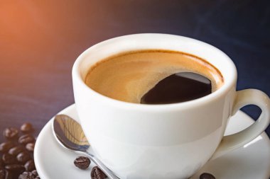 Kahve fincanı ve karanlık bir arka plan üzerinde fasulye