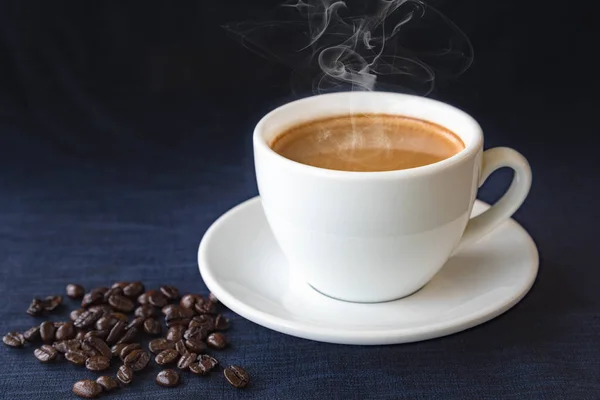 Xícara de café e grãos em um fundo escuro — Fotografia de Stock