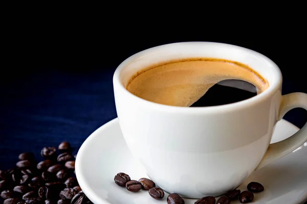 Xícara de café e grãos em um fundo escuro — Fotografia de Stock