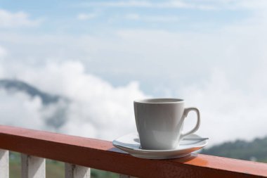 Beyaz açık na ile balkon kenarında sıcak kahve fincan kapatmak