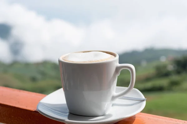 Close up tazza bianca di caffè caldo sul bordo del balcone con na esterna — Foto Stock