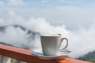 Beyaz açık na ile balkon kenarında sıcak kahve fincan kapatmak