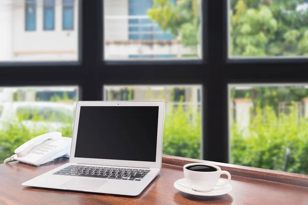 木製の机の上の白いコーヒーのマグカップ付きのノート パソコン — ストック写真