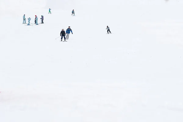 Skifahrer und Snowboarder auf einer Skipiste — Stockfoto