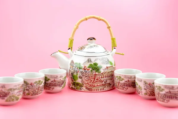 Teekanne mit Tassen auf rosa Hintergrund. — Stockfoto