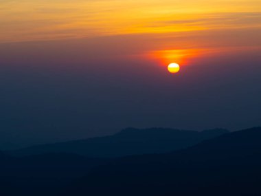Dağlar manzaralı. Bulutlu gökyüzünde dramatik gün batımı. Turuncu gökyüzünde gümüş astar ve bulutla güçlü bir gün doğumu.