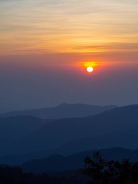Dağlar manzaralı. Bulutlu gökyüzünde dramatik gün batımı. Turuncu gökyüzünde gümüş astar ve bulutla güçlü bir gün doğumu.