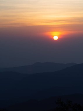 Dağlar manzaralı. Bulutlu gökyüzünde dramatik gün batımı. Turuncu gökyüzünde gümüş astar ve bulutla güçlü bir gün doğumu.