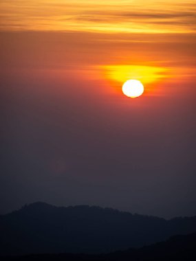 Dağlar manzaralı. Bulutlu gökyüzünde dramatik gün batımı. Turuncu gökyüzünde gümüş astar ve bulutla güçlü bir gün doğumu.