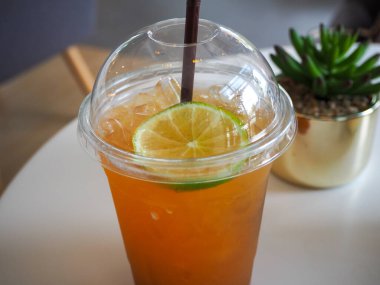 Limonlu soğuk buzlu çay ve paket plastik bardakta saman. Soğuk, ferahlatıcı kokteyller. Plastik bardakta limonlu çay kokteyli kolasını çıkar..