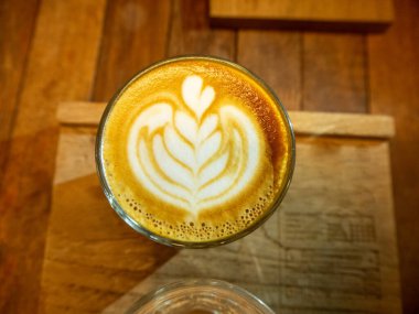 Güzel Latte sanatıyla birlikte bir fincan kahve. Kahve fincanı ve ahşap masa üzerinde kahve sanatı..