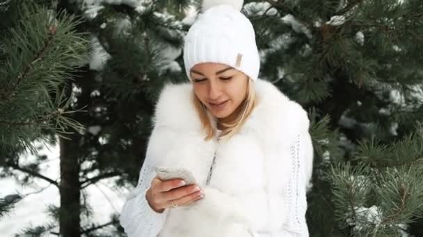 Mooie vrouw luistert naar muziek in oortelefoons, winterlandschap. — Stockvideo