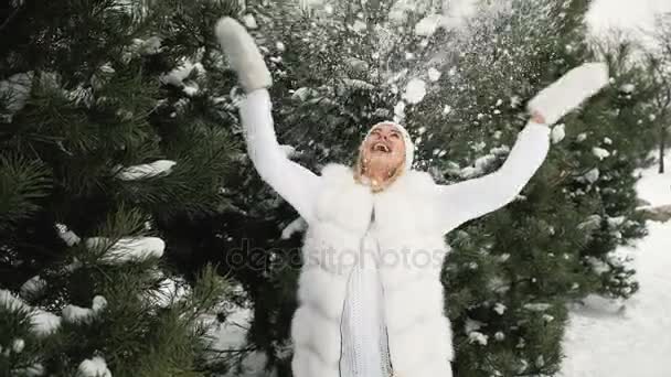 Charming blonde plays with snow against background of winter landscape — Stock Video