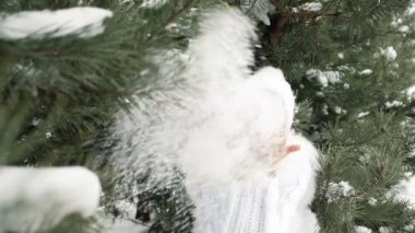 Elleri kar üzerinde üfleme beyaz elbiseli kadın gülüyor