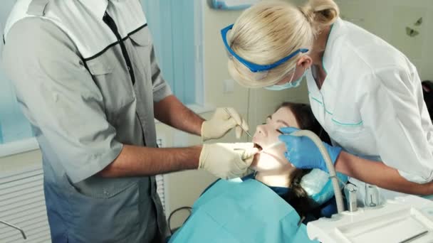 Dentista con strumenti ispeziona la mascella del paziente seduto su una sedia . — Video Stock