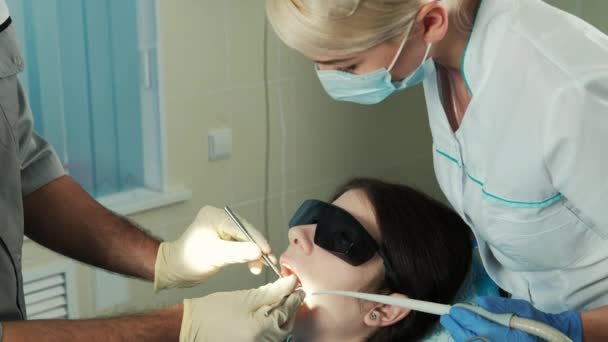 Asistente supervisa el tratamiento de trabajo del dentista en el consultorio dental — Vídeo de stock