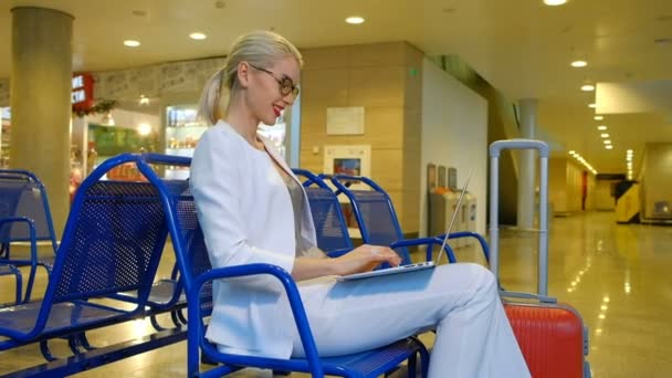 Passageiros loiros sentados no corredor de partida conversando no laptop — Vídeo de Stock