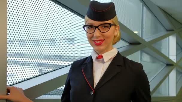 Dans hôtesse de l'aéroport avec les cheveux blonds et des lunettes souriant affablement . — Video