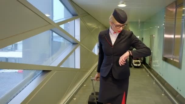 En el aeropuerto azafata con maleta va y mira su reloj . — Vídeos de Stock