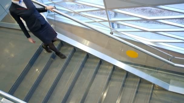 Esbelta azafata joven con gafas baja por las escaleras del aeropuerto . — Vídeos de Stock