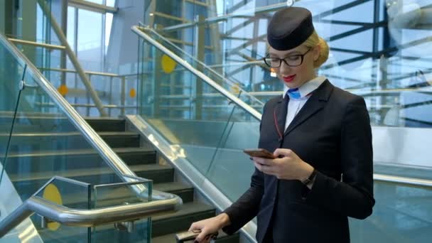 Flygvärdinna på flygplatsen med en telefon i hennes händer hjälper passagerare. — Stockvideo