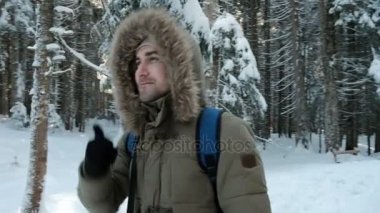 Kışın çam ormanı içinde açık havada yürüyen genç adam