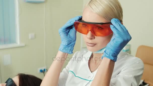 Νέοι όμορφη οδοντίατρος βάζοντας uv προστασία σε πριν από την εργασία στη Στοματολογία. — Αρχείο Βίντεο
