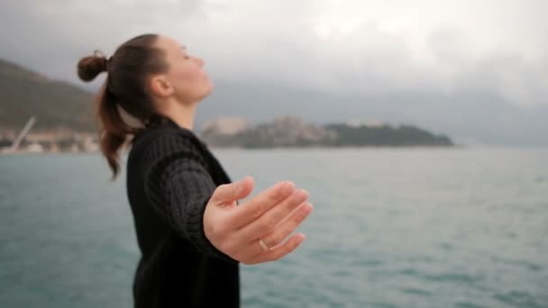 湖でカジュアルなヘアスタイルの女性は彼女の腕を開いて、目を閉じた. — ストック動画