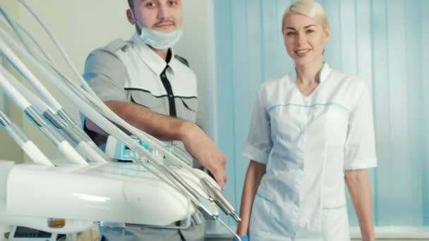 Стоматолог зі своїм помічником стоїть біля щасливого пацієнта в спеціальному кріслі . — стокове відео