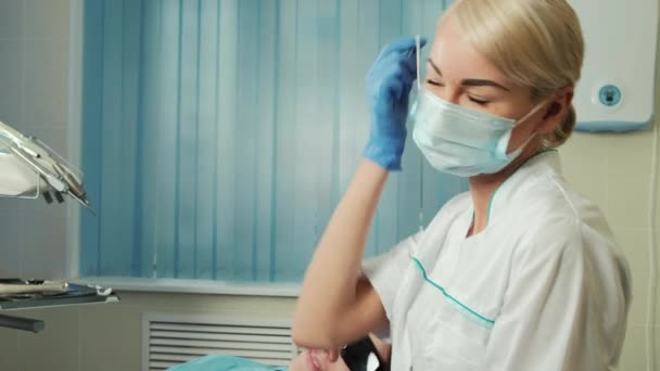 Young beautiful blond woman take off mask in dental office. — Stock Video