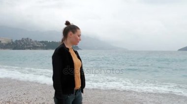 Dalgalar ile Sahilde yürüyüş bulutlu sisli sabah kadında.