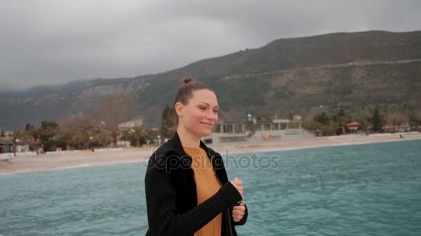 Femme souriante et courant sur la jetée sur le front de mer dans les collines . — Video