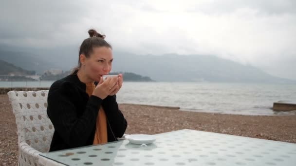 I kaféet på stranden av en kvinna som dricker varm dryck. — Stockvideo