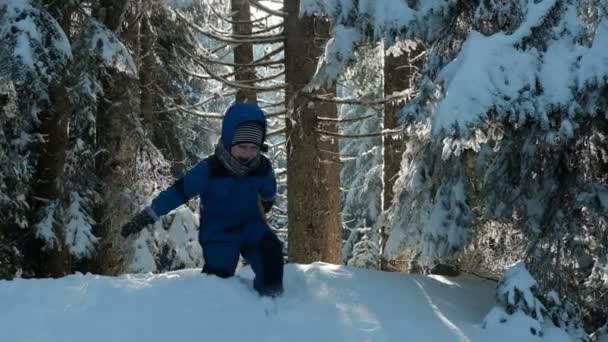 Niño en traje deportivo azul rodó la cabeza sobre los talones de colina de nieve — Vídeo de stock