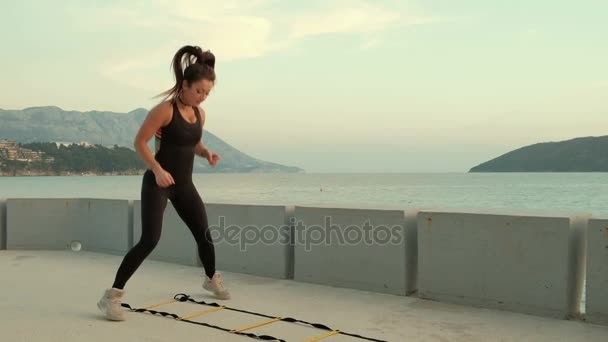 Sportovkyně, skákání na pobřeží na speciální šablony pásů. — Stock video