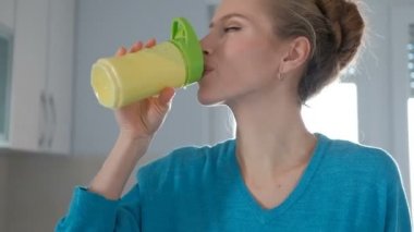 Sağlıklı suyu sarı Şişeden içme zevk ile genç kadın.