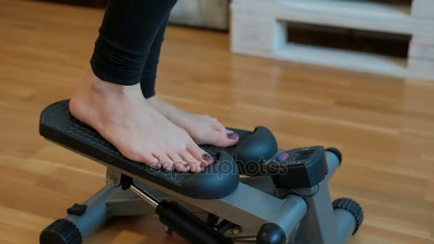 A mulher do quarto realiza um exercício para as pernas no mini stepper . — Vídeo de Stock