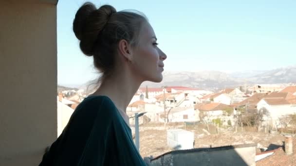 Kvinnan ser ut från balkongen och beundra staden på sommaren. — Stockvideo