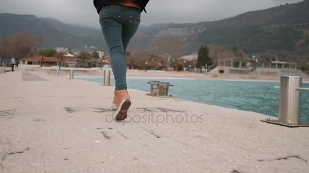 Frau läuft entlang Seebrücke, Böschung in der Nähe See. Blick von hinten. — Stockvideo