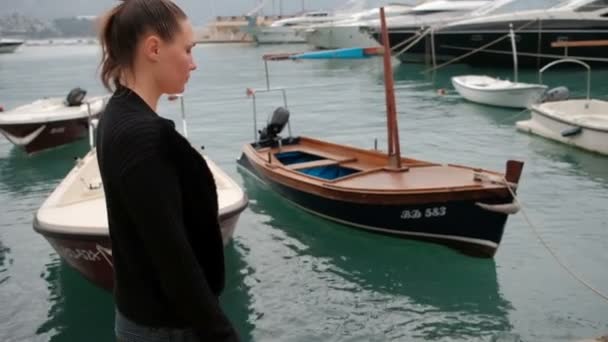 Mujer adulta caminar a lo largo del muelle con diferentes embarcaciones amarradas . — Vídeos de Stock