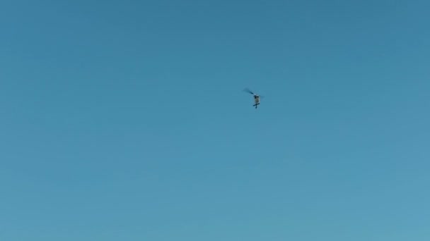 Вертоліт літає в блакитному небі, літає, стріляючи екіпажем камери на відкритому повітрі — стокове відео